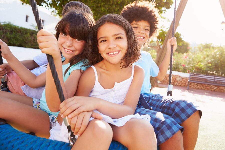 Group of young kids smiling and happy while swinging together.