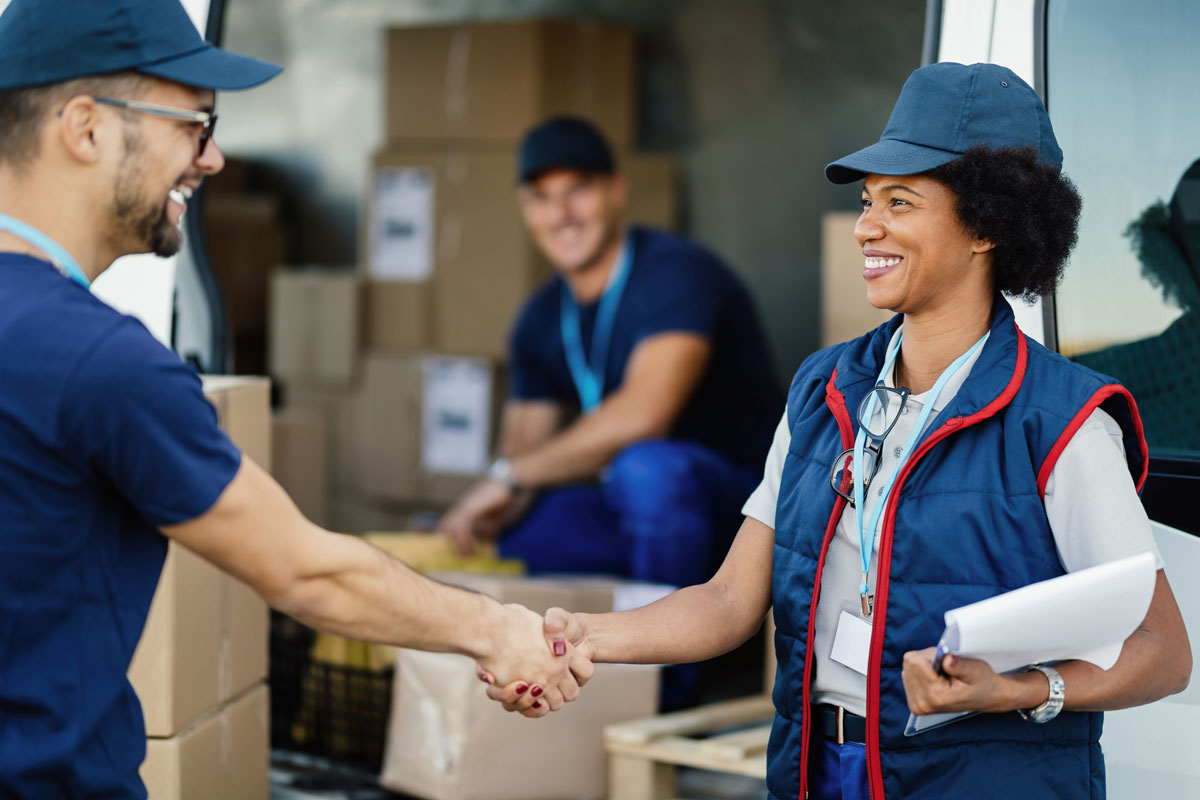 Delivery workers smiling while shaking hands.