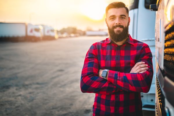 Young male standing in front of work truck with arms crossed and sun setting in the background.