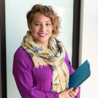 Professional women wearing purple shirt holding clipboard.