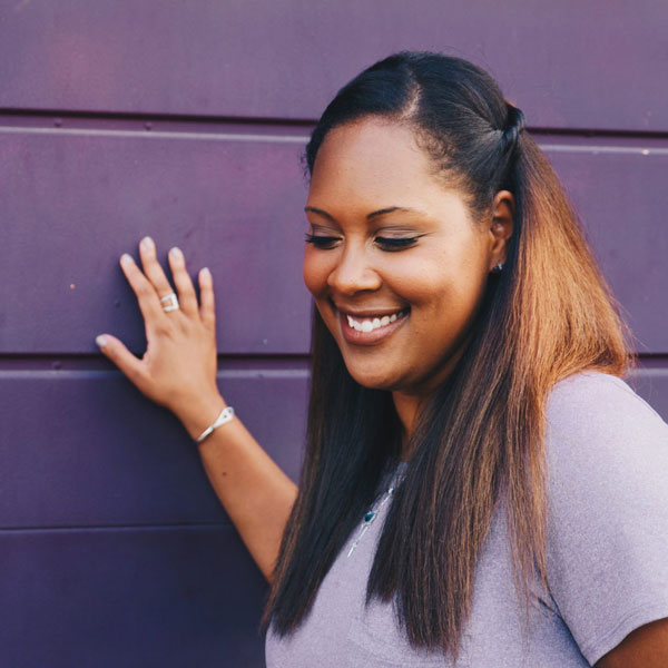 Women in purple shirt standing outside next to purple wall