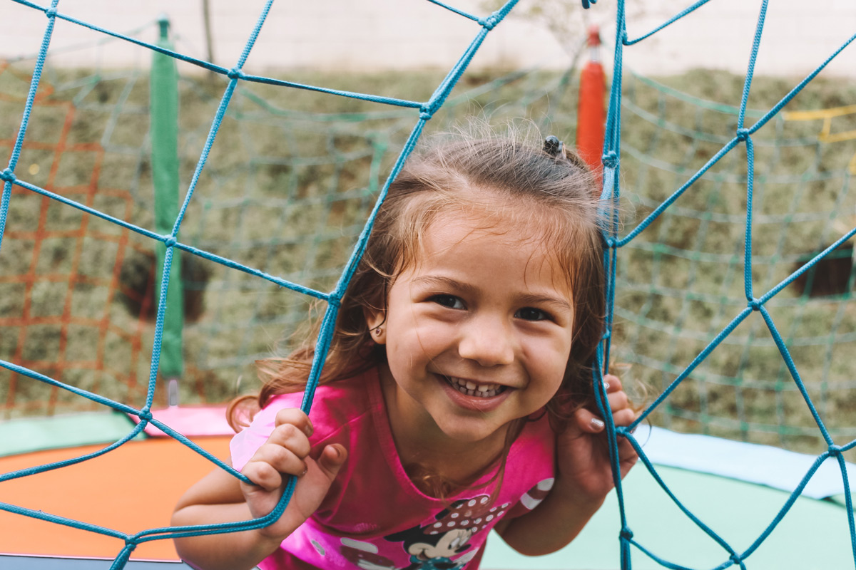 Little girl in pink shirt smiling outside.