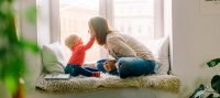 toddler holds her Mom's face in her hands