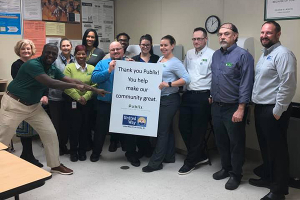 United Way employees and Publix employees standing together with a Thank you for contributing sign for Publix