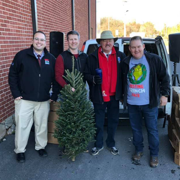 Four men standing together with small Christmas tree