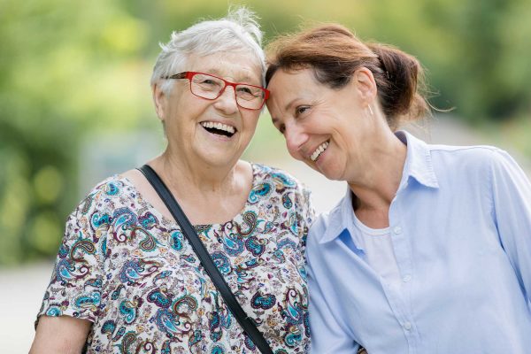 Two older women happily walking together outside.