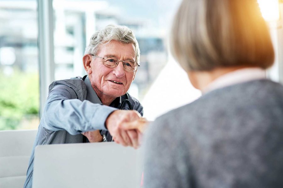 Older gentlemen shaking hands with women across a desk.