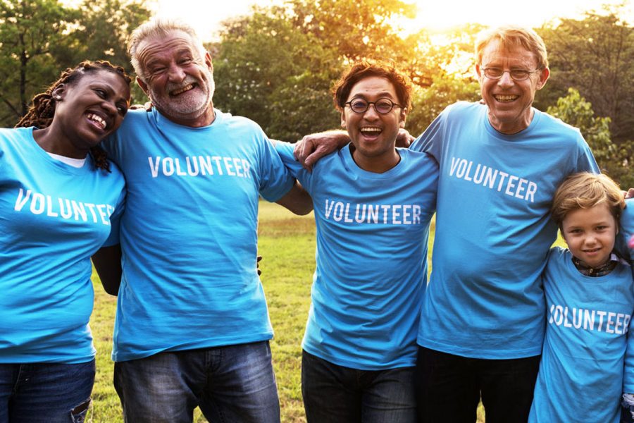 United Way volunteers in blue shirts smiling outside together.