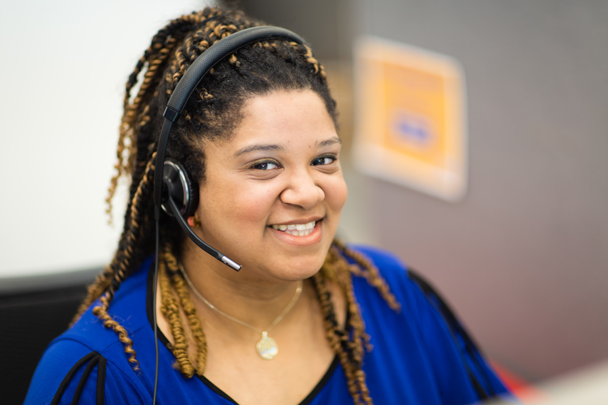 Women in blue shirt smiling with headset on.