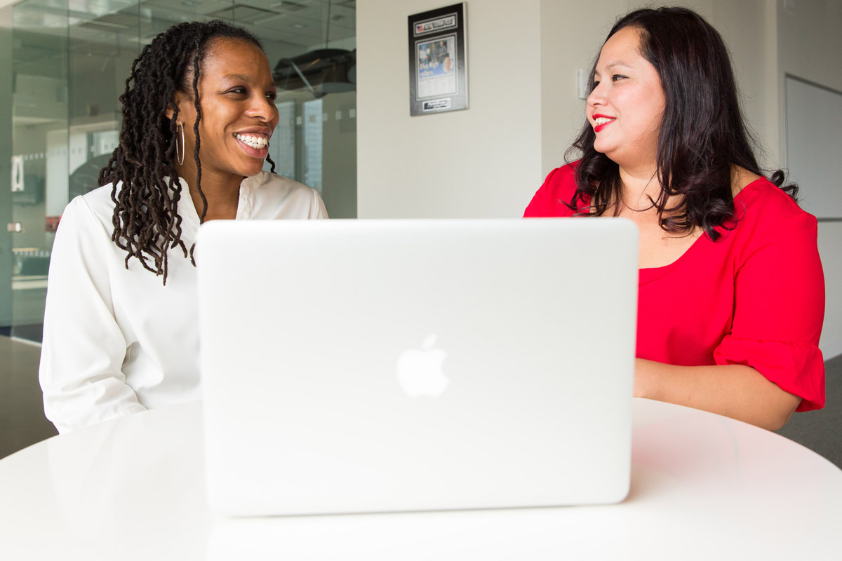 Two women with laptop discussing a workplace giving campaign with United Way
